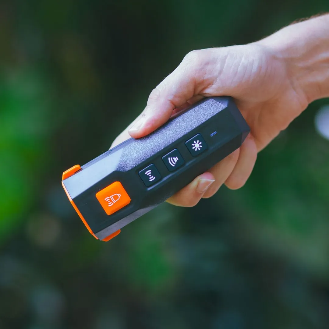 Dog owner using ultrasonic dog training device on a walk